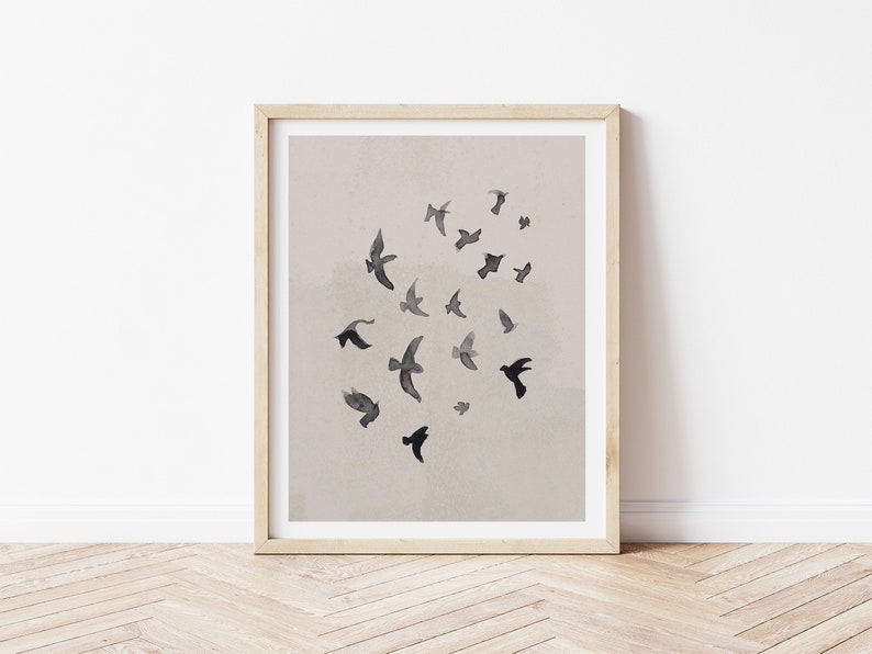 Pu&ograve; includere: Una stampa incorniciata con un design minimalista che presenta un gruppo di uccelli neri in volo su uno sfondo beige chiaro.