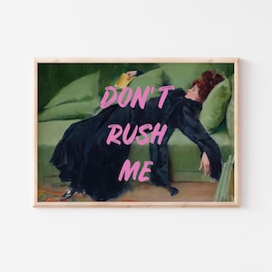 May include: Framed art print featuring a woman in a black dress reclining on a green sofa. The words "DON'T RUSH ME" are written in pink across the image. The artwork has a vintage aesthetic.