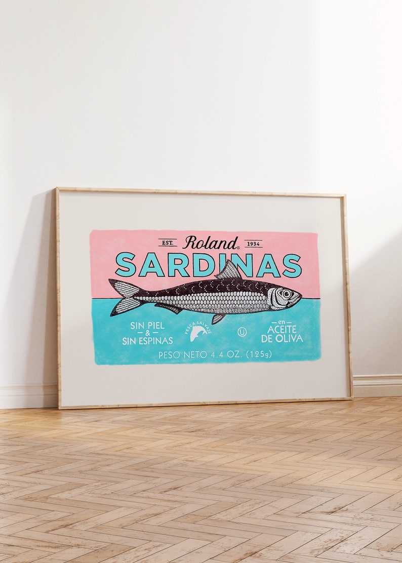 May include: A vintage-style label for sardines in olive oil. The label is pink and blue with a black and white illustration of a sardine. The text on the label reads "EST. Roland 1934 SARDINAS SIN PIEL & SIN ESPINAS -en- ACEITE DE OLIVA PESO NETO 4.4 OZ. (125g)"