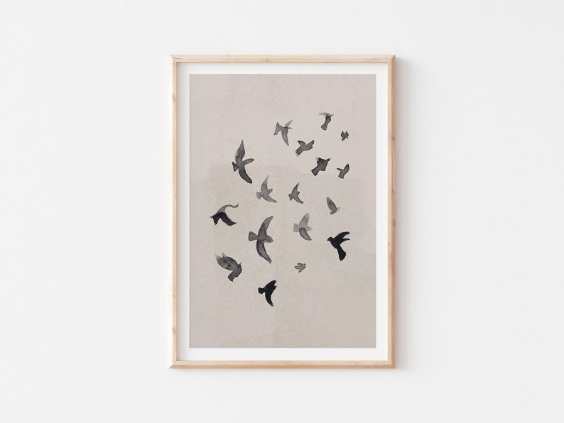 Pu&ograve; includere: Una stampa incorniciata con un design minimalista che presenta uno stormo di uccelli neri che volano su uno sfondo beige chiaro.