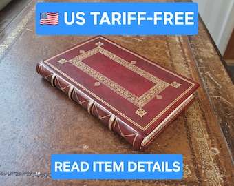May include: A closed, rectangular book with a burgundy leather cover and gold decorative accents. The book has a gold-edged spine and a gold-bordered rectangle on the cover. The text "READ ITEM DETAILS" is in a blue banner.