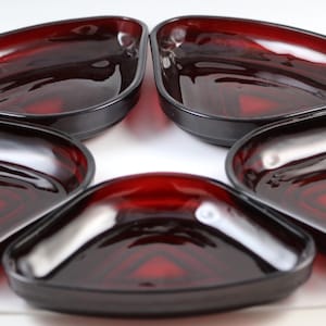 May include: Set of five red glass triangular dishes. The dishes are made of clear glass with a red tint and have a smooth, glossy finish.