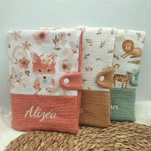 Peut inclure: Trois matelas à langer pour bébé avec différents motifs. L'un présente un renard avec des accents floraux et le nom "Alizea" brodé en blanc. Les deux autres ont des illustrations d'animaux et des fermetures à bouton. Les coussins ont un aspect texturé et superposé.