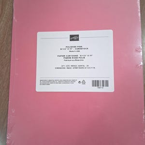 May include: A pack of 24 sheets of Polished Pink cardstock measuring 8-1/2 inches by 11 inches. The package is wrapped in clear plastic and features a white label with the Stampin' Up! logo, product name, and manufacturing information.