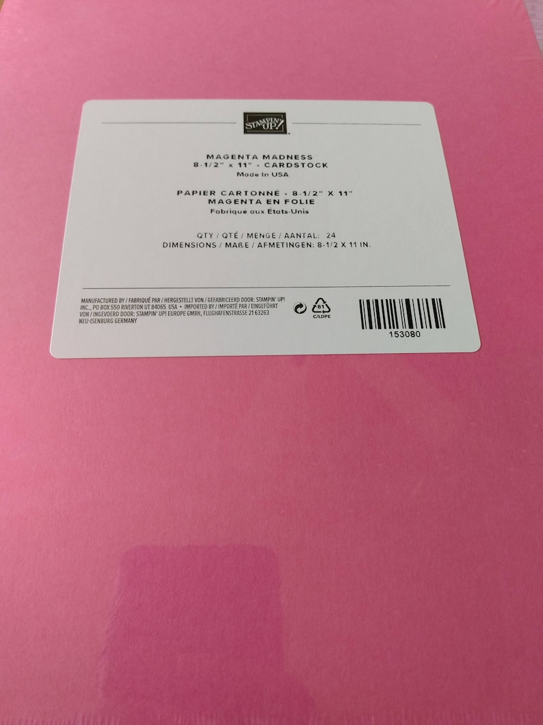 May include: A pack of Magenta Madness cardstock by Stampin' Up! with a white label. The label reads: Magenta Madness 8-1/2 x 11 Cardstock, Made in USA, Qty 24, Dimensions 8-1/2 x 11 in. The bright pink paper is visible beneath the rectangular label.