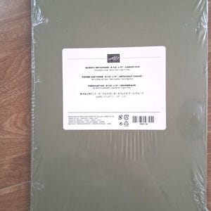 May include: A pack of olive green Stampin' Up! cardstock in clear plastic wrap. The white label reads Always Artichoke 8-1/2 x 11 cardstock, 24 sheets total, acid free, lignin free, with additional text in French, German, and Japanese.