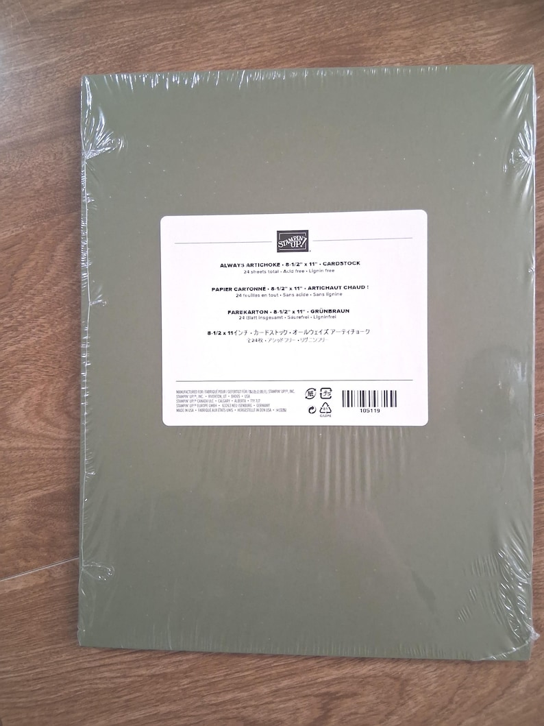 May include: A pack of olive green Stampin' Up! cardstock in clear plastic wrap. The white label reads Always Artichoke 8-1/2 x 11 cardstock, 24 sheets total, acid free, lignin free, with additional text in French, German, and Japanese.