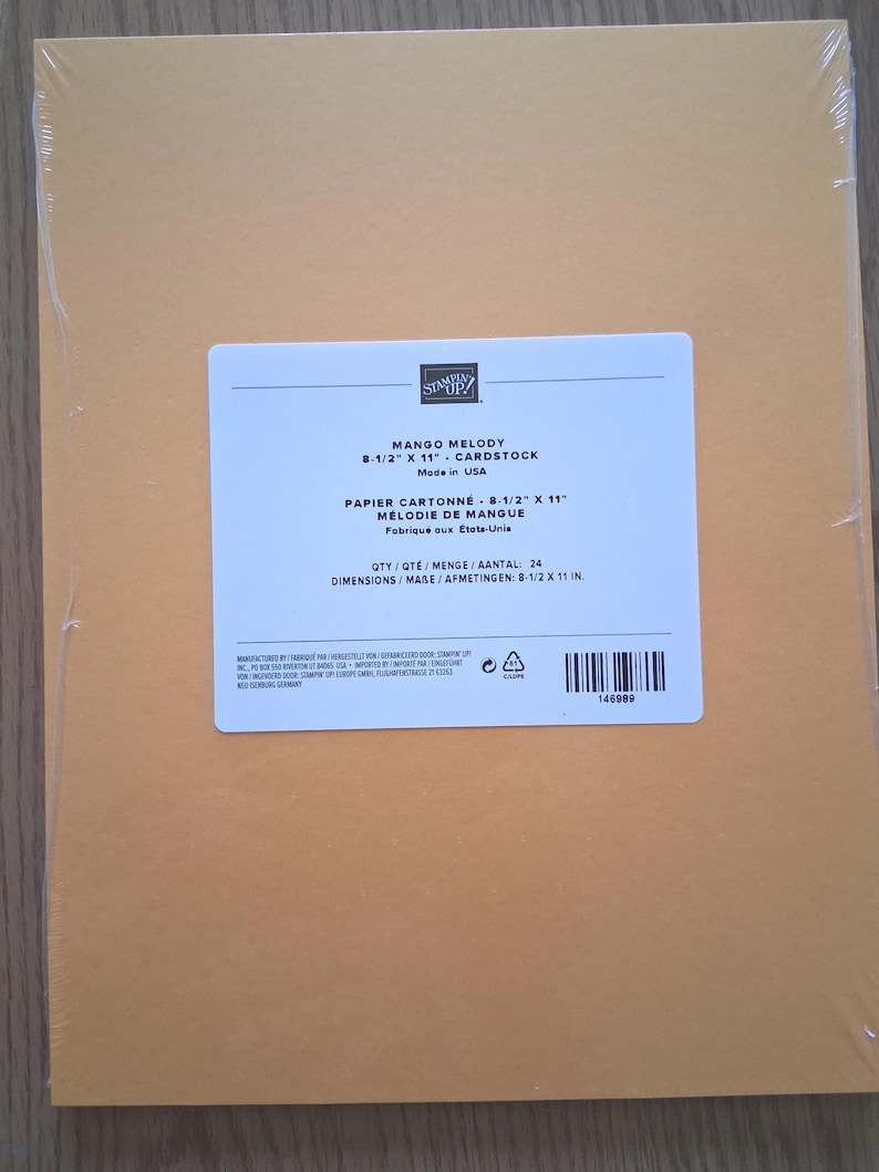 May include: A pack of 24 sheets of Mango Melody cardstock measuring 8-1/2 inches by 11 inches, sealed in clear plastic. The white label features the Stampin' Up! logo, product name, quantity, and dimensions in both English and French.
