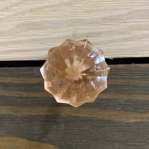 May include: A clear, faceted, pink glass knob for a drawer or cabinet.