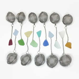 May include: Eight silver tea infusers with chains and colorful glass charms. The charms are in shades of red, green, blue, and yellow.