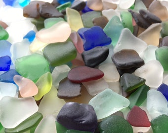 May include: A collection of colorful sea glass pieces in various shapes and sizes. The sea glass is a mix of green, blue, brown, red, and white.