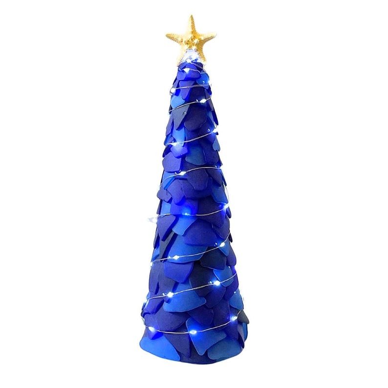 May include: A decorative blue Christmas tree with a gold starfish topper. The tree is adorned with blue and white lights. The tree is made of layered blue material.