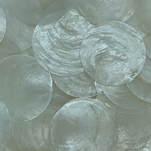 May include: Close-up of a collection of iridescent, round, mother-of-pearl shell pieces. The shells have a pearlescent sheen and a slightly textured surface. The arrangement creates a shimmering, organic pattern, ideal for craft projects or decorative purposes.