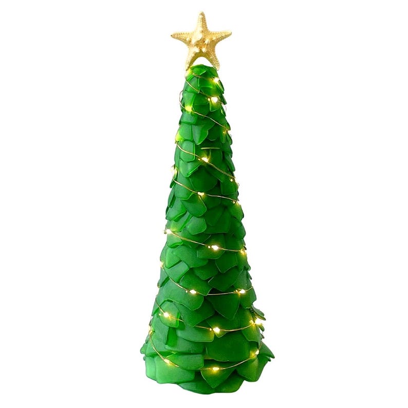 May include: A green decorative Christmas tree with a gold starfish topper. The tree is adorned with small, warm white lights. The tree is made of green glass pieces.