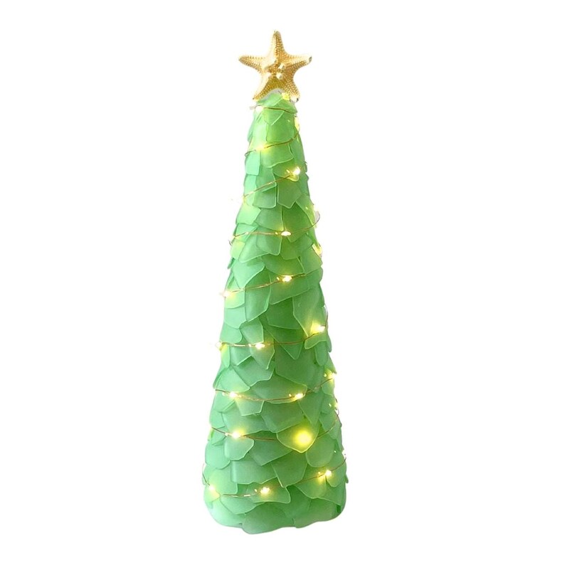 May include: A decorative green Christmas tree with a gold starfish topper. The tree is adorned with small, warm white lights. The tree is made of a soft, leaf-like material.