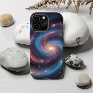 Puede incluir: Una funda de teléfono negra con un diseño de galaxia giratoria en tonos azules, morados y rosas. La funda tiene un recorte para el objetivo de la cámara del teléfono.
