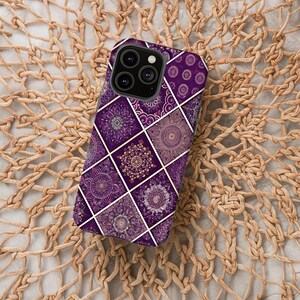 May include: A purple phone case featuring a geometric mandala design. The case is divided into squares with white lines, each containing a different mandala pattern in shades of purple and gold. The phone case rests on a woven, beige surface.