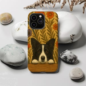 May include: A phone case featuring a black and white Border Collie dog design. The case has a floral pattern in orange, purple, and green on a gold background. The dog is peeking over a wooden ledge.