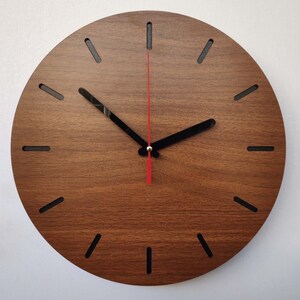 May include: A round wooden clock with black hour markers and a red second hand. The clock face is made of a dark wood with a wood grain pattern.