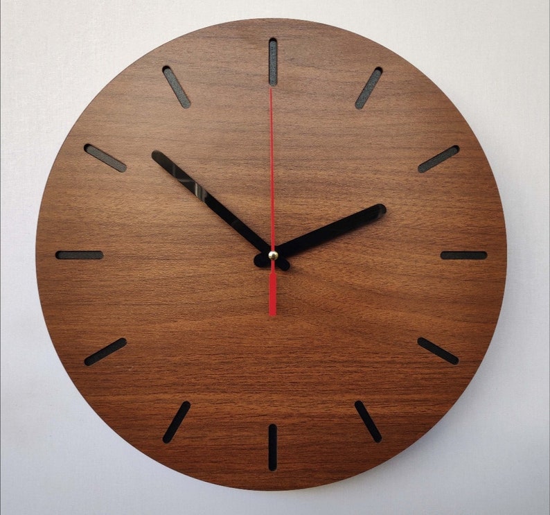 May include: A round wooden clock with black hour markers and a red second hand. The clock face is made of a dark wood with a wood grain pattern.
