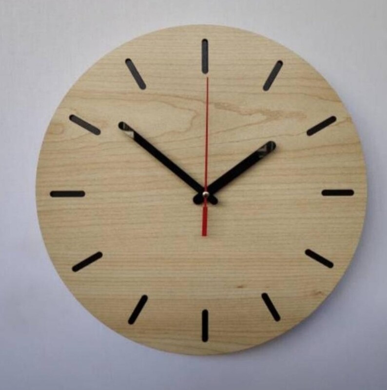 May include: A round wooden wall clock with black hour and minute hands and a red second hand. The clock face has a light wood grain finish and black hour markers.