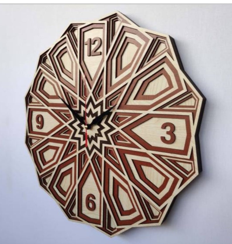 May include: A wooden clock with a geometric design in shades of brown and red. The clock face features Roman numerals for the hours and a starburst design in the center.