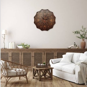 May include: A brown wooden clock with a geometric design and black Roman numerals. The clock is hanging on a white wall above a wooden cabinet and a white couch.