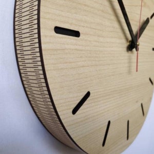 May include: A round wooden clock with black hour and minute hands and a red second hand. The clock face has a light wood grain pattern and black hour markers.