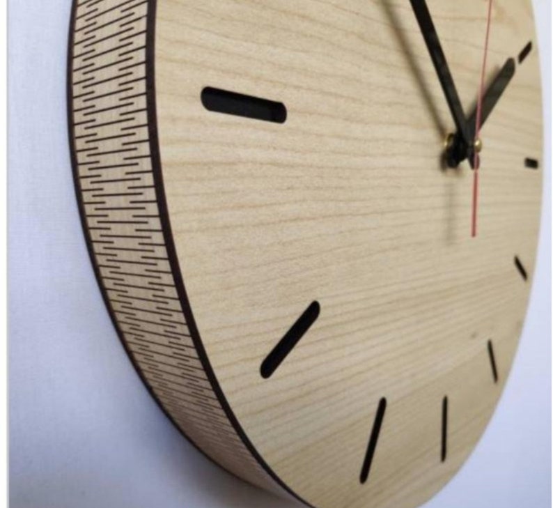 May include: A round wooden clock with black hour and minute hands and a red second hand. The clock face has a light wood grain pattern and black hour markers.