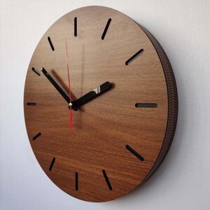 May include: A brown wooden wall clock with black hour markers and black hands. The clock has a red second hand.