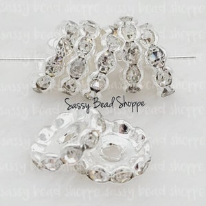 May include: Silver-toned metal bead caps with clear rhinestone accents. The bead caps are designed to be used as end caps for jewelry making.