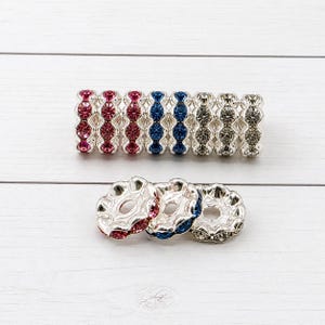 May include: An assortment of rhinestone bracelets and decorative metal beads. The bracelets feature alternating sections of red, blue, and clear rhinestones. The beads are silver with red, blue, and clear rhinestone accents.