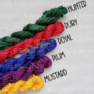 May include: Six spools of waxed cord in different colors: hunter green, ruby red, royal blue, plum purple, and mustard yellow. The spools are labeled with the color names.