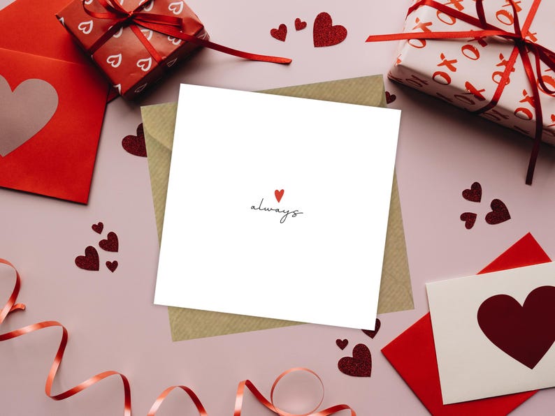 Peut inclure: Une carte blanche avec une enveloppe brune. La carte a un petit c&oelig;ur rouge et le mot "toujours" &eacute;crit en cursive noire. La carte est entour&eacute;e de c&oelig;urs rouges et d'autres d&eacute;corations de la Saint-Valentin.