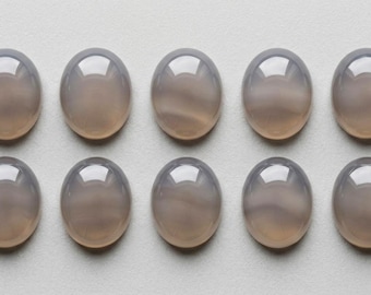 May include: Ten smooth, oval-shaped cabochons arranged in two rows of five. Each cabochon is a translucent, muted grey-brown colour with a polished, reflective surface that catches the light, creating a soft, rounded highlight on the top.