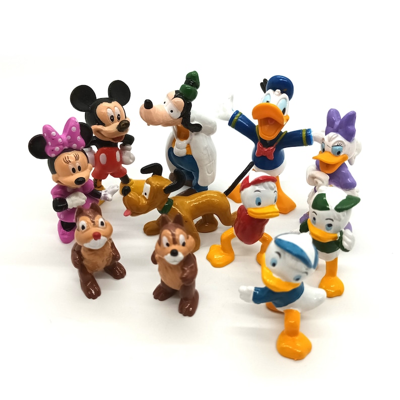 Pode incluir: Uma cole&ccedil;&atilde;o de figuras de personagens da Disney, incluindo Mickey Mouse, Minnie Mouse, Pato Donald, Margarida, Pateta, Pluto e Tico e Teco. As figuras s&atilde;o coloridas e est&atilde;o sobre uma superf&iacute;cie branca.