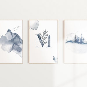 Può includere: Set di tre stampe ad acquerello che rappresentano una catena montuosa, la lettera M con accenti floreali e una scena di bosco. Le stampe sono in tonalità di blu e grigio su uno sfondo bianco.