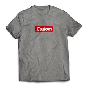 May include: A gray t-shirt with a red box that says "Custom" in white letters.