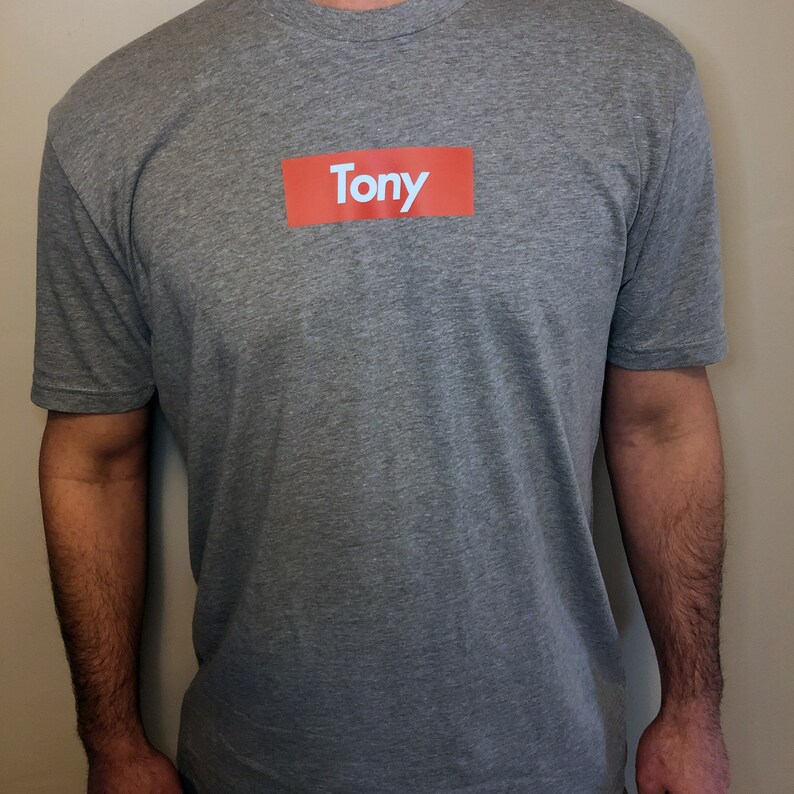May include: A gray t-shirt with a red box that says "Tony" on it.