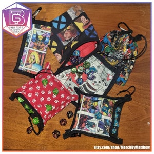 May include: Five different dice bags with various comic book character designs. The bags are made of fabric and have a drawstring closure. The bags are filled with dice, which are also visible in the image. The text "etsy.com/shop/MerchByMatthew" is visible at the bottom of the image.