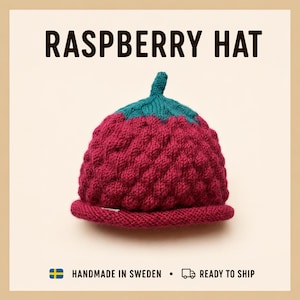Könnte beinhalten: Eine gestrickte Mütze mit einem texturierten, himbeerartigen Muster in tiefem Magenta, gekrönt von einem kleinen grünen stielartigen Detail. Der Text RASPBERRY HAT ist in Schwarz über der Mütze gedruckt, mit weiterem Text unter der Mütze.