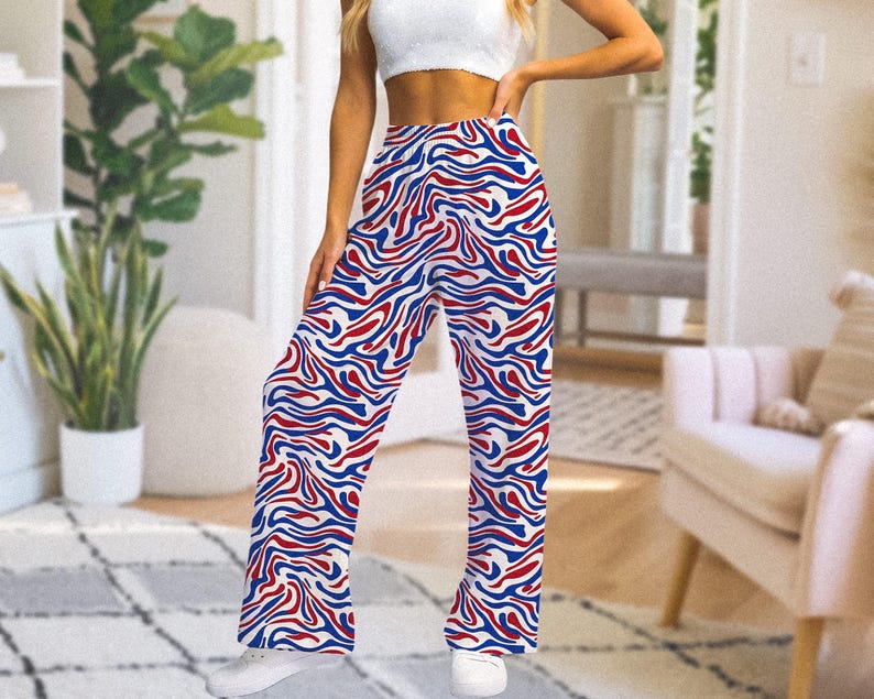 Op de afbeelding: Broek met wijde pijpen met een levendig patroon van rode en blauwe golvende lijnen op een witte achtergrond. De broek heeft een hoge taille en is gemaakt van een lichte stof. De broek maakt deel uit van een casual kledingcollectie.
