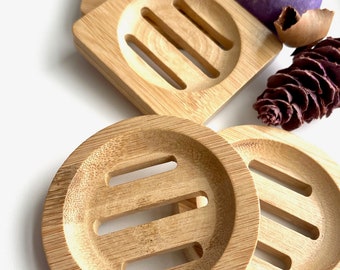 May include: Four wooden soap dishes with a slatted design. The dishes are made of natural bamboo and are perfect for holding soap bars.