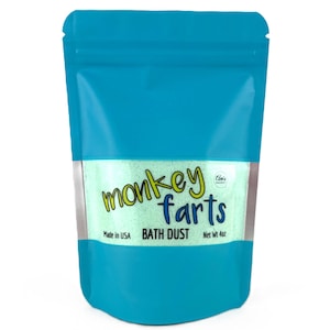 May include: A turquoise pouch containing green bath dust. The words "monkey farts" are written in a playful font. The text "BATH DUST" and "Net wt 4oz" are also visible. The pouch is sealed and made in the USA.