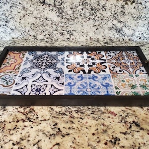 May include: A rectangular wooden serving tray with a black frame and a colorful tile design. The tiles are a mix of blue, white, yellow, and green.