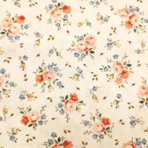 Może przedstawiać: Zbliżenie kremowej tkaniny z kwiatowym wzorem. Wzór przedstawia skupiska różowych i pomarańczowych róż, małych niebieskich kwiatów i rozproszonych brązowych kształtów liści. Projekt jest delikatny i szczegółowy.