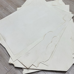Peut inclure: Une pile de feuilles de papier blanc cassé de formes irrégulières. Certaines feuilles ont des bords festonnés décoratifs. Le papier a une surface légèrement texturée. Les feuilles semblent neuves et non utilisées.