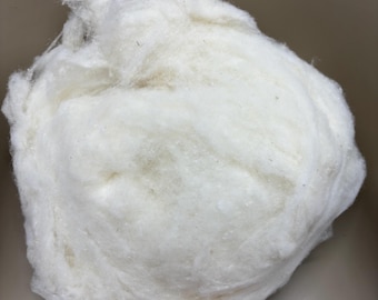 May include: A large clump of white cotton fiber. The cotton is soft and fluffy, and it appears to be natural.