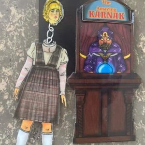 May include: A pair of earrings featuring a cartoon image of a woman with a plaid dress and a fortune teller with a crystal ball. The fortune teller's sign reads "The Amazing Karnak".