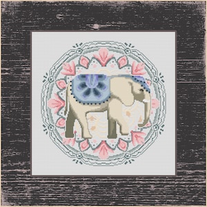 May include: A cross-stitch design of an elephant with a blue and white saddle, set against a floral mandala pattern in pink, green, and white. The artwork is framed in a dark, distressed wooden border.